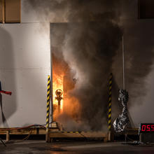 smoke billows from the open doorway of a burning test storage room