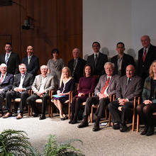 6 men and 3 women seated in front, 1 woman and 8 men standing behind