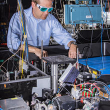 Man in glasses stands behind a table with a number of wires and lattices.