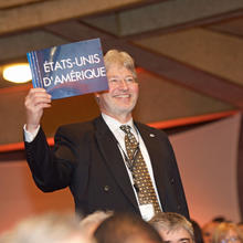 Walt Copan holds up a card that says Etats-Unis D'Amerique