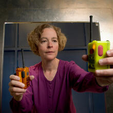 woman holding two communications (radio) devices