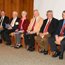 The nine Portrait Gallery inductees sit in a row of chairs.