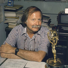 man seated at his desk with Emmy