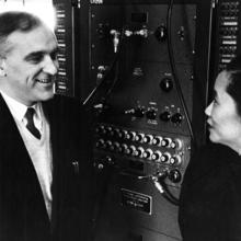 Ernest Ambler and Chien-Shiung Wu in front of a control panel 