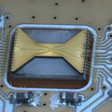 A rectangular chip features a brass-colored bow-tie shape on black background.