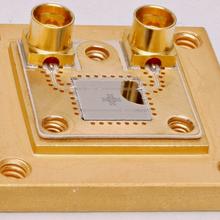 Gold-colored metal square has connectors and chip in center.