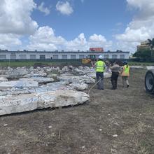 Broken pieces of concrete marked with blue spray paint lay on the ground near a storage facility. 