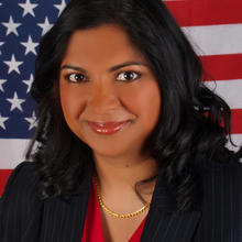 Pravina Raghavan poses with the American flag behind her.