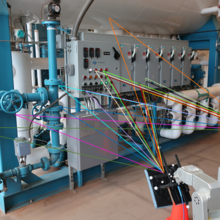 Wireless testing equipment is shown inside a building with transmission lines drawn over the photo in various colors.