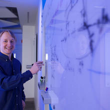 Alexey Gorshkov poses at a whiteboard, holding a marker. 