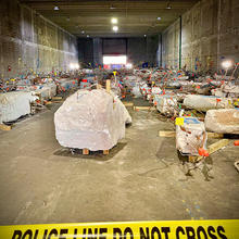 Large chunks of concrete bristling with rebar and colored flags sit in a warehouse. 