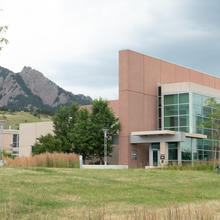 An angular office building is to the right, with lower building to the left and mountains in the background.