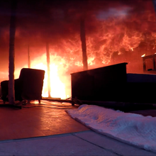 Flames roll on the ceiling of a darkened burning test room one minute before a flashover occurs.