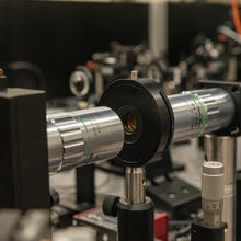 Optical equipment includes a horizontal metal tube with a black cap on the end and a hole for light to shine through.