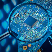 A photo of a magnifying glass highlighting a circuit board