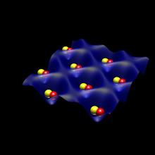 Black background. Blue structure that looks like an egg carton with red and yellow globes in each pocket 