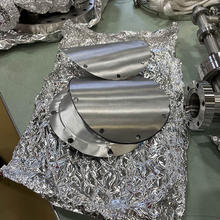 Disk-shaped pieces of aluminum are scattered on a lab table along with aluminum foil.