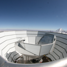 Cup-shaped telescope structure surrounded by larger cup-shaped shield on a clear day. 