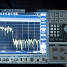 Radio signal analyzer has screen on the left, showing a wave chart, and buttons and dials on the right. 
