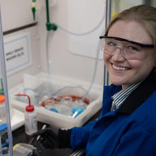 Christine McGinn wears safety glasses as she handles plastic bottles and other materials in the lab. 