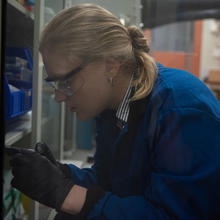 Christine McGinn wears safety glasses as she bends over her work in the lab. 