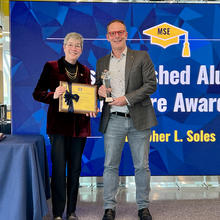 Two people posing with an award