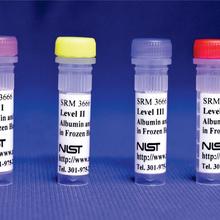 Four plastic vials with different colored lids are displayed standing up, with labels that say SRM 3666 and NIST. 