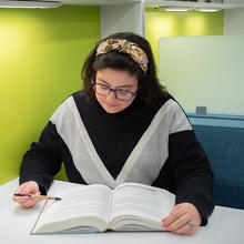 Kathryn Miller sits reading a book at a small table in the NIST library. 
