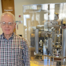 Antonio Possolo stands next to a museum display of a Kibble balance, a complex scientific device.