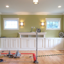 A living room is empty except for built-in cabinetry and scientific equipment, including four small heaters on the floor with associated wiring. 