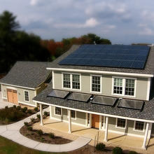 A newly built two-story home with an attached garage has solar panels on the roof.