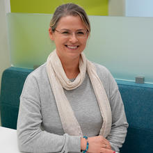 Justyna Zwolak poses smiling, seated at a colorful workspace in the NIST library. 