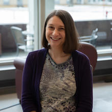 Julie Haney poses smiling for a casual portrait in the NIST library. 
