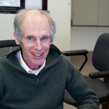 Alexander Kramida smiles for a portrait sitting at his desk.