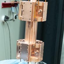 A copper-colored metal device has a vertical tube running through two separate chambers.