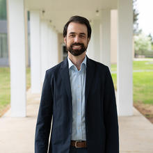 Corey Stambaugh poses smiling outdoors on the NIST campus.