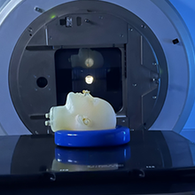 A model of a human head lies face up on the platform of an MRI machine. 