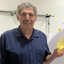 Stephen Russek poses in the lab holding a small model of a human head.
