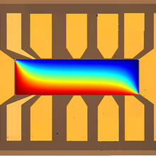 Microscope image shows rectangular shape with bright colors running across horizontally: red at the bottom shading into blue at the top. 