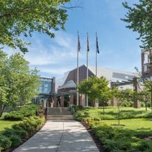 Outdoor photo of a walkway leading up to a building with three flag poles
