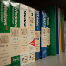 Boxes of Microsoft Windows software with NSRL stickers are lined up on a metal shelf.