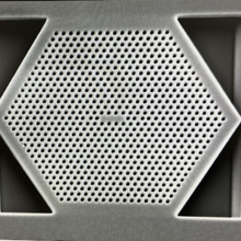 Close-up view of a hexagon shape with rows of tiny holes filling it. 