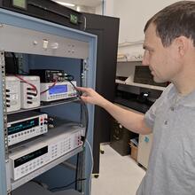 Matt Spidell stands looking into a server cabinet that holds several electronic devices wired together.