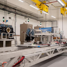 Complex scientific devices and wiring sit on a platform in front of three large X-ray machines. 