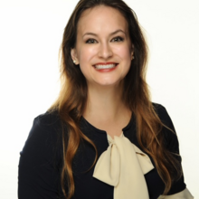 Smiling woman in a navy blue and white dress.