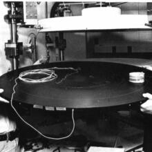 Two men with a large circular object. black & white