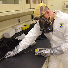 Man in gas mask and bunny suit with a handheld device