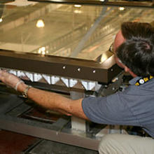 NIST technician Dana Strawbridge bolts the top frame of the map encasement to its base during a test sealing of the encasement prior to shipping to the Library of Congress.