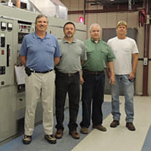 NIST engineer Matthew Deutch and technicians Douglas Sutton, Glenn Nelson, and Bill Yates (left to right) are shown with one of three WWVB transmitters as it broadcasts the station's signal in 2013.