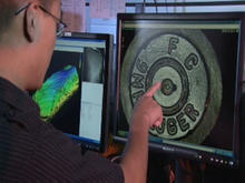NIST engineer pointing at a firing pin impression.